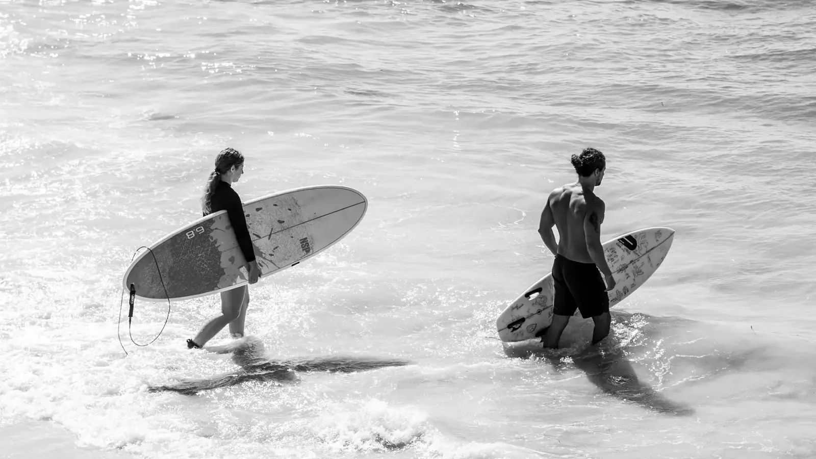 Two surfers with their boards walking into the water on the south coast of Sri Lanka